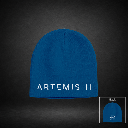 Blue beanie with 'ARTEMIS II' text on one side and NASA Meatball Logo on the other side on a dark background