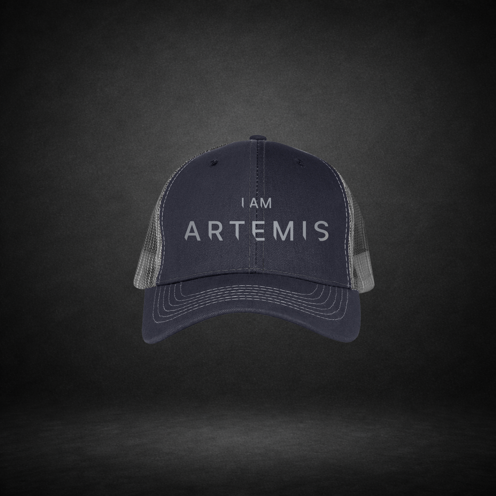 Navy blue cap with 'I AM ARTEMIS' text on a dark gray background