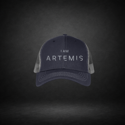 Navy blue cap with 'I AM ARTEMIS' text on a dark gray background